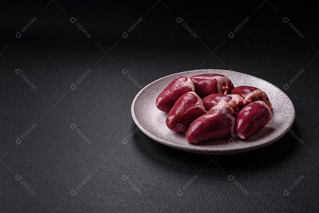 Corações crus de peru ou frango com sal e especiarias sobre um fundo escuro de concreto