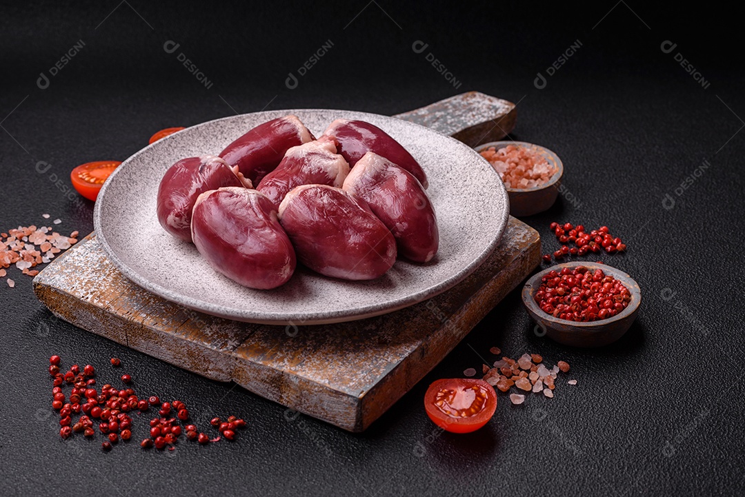 Corações crus de peru ou frango com sal e especiarias sobre um fundo escuro de concreto