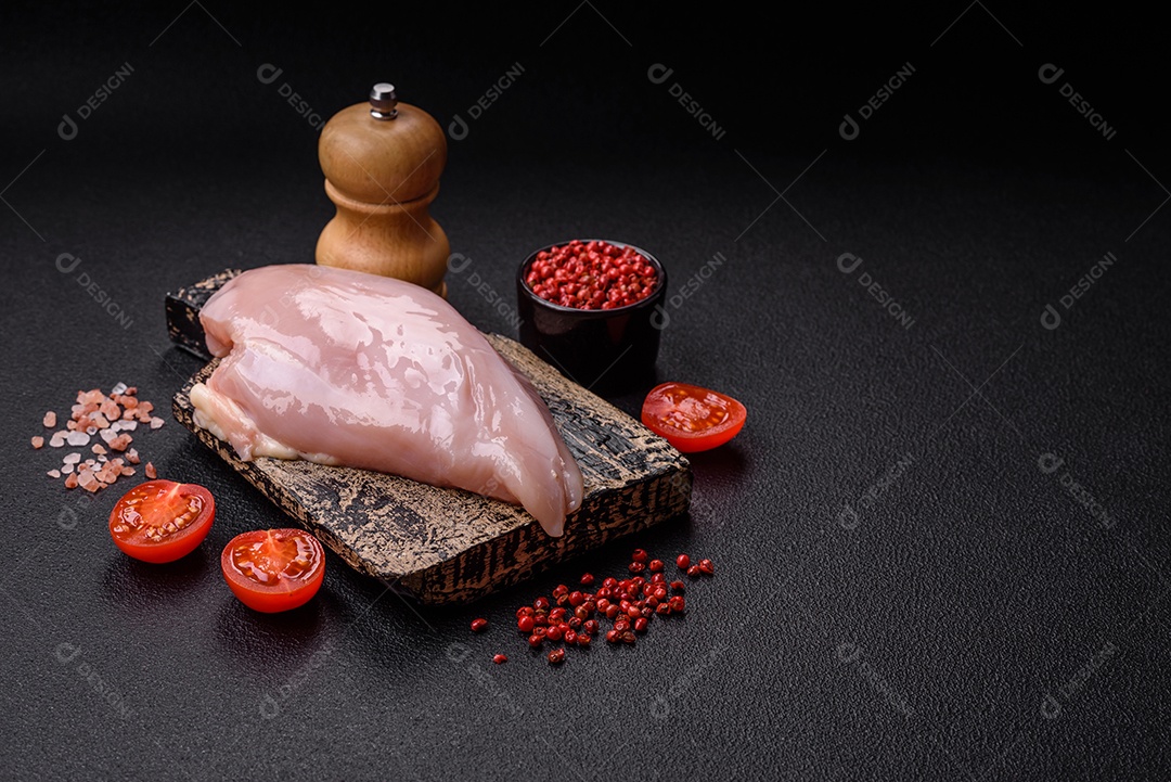 Filé de frango fresco sobre uma mesa de concreto escuro com especiarias e ervas. Preparação para cozinhar pratos de carne