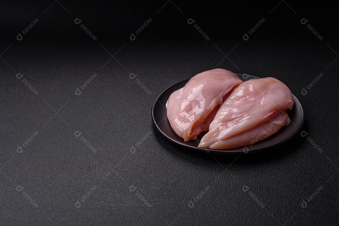 Filé de frango fresco sobre uma mesa de concreto escuro com especiarias e ervas. Preparação para cozinhar pratos de carne