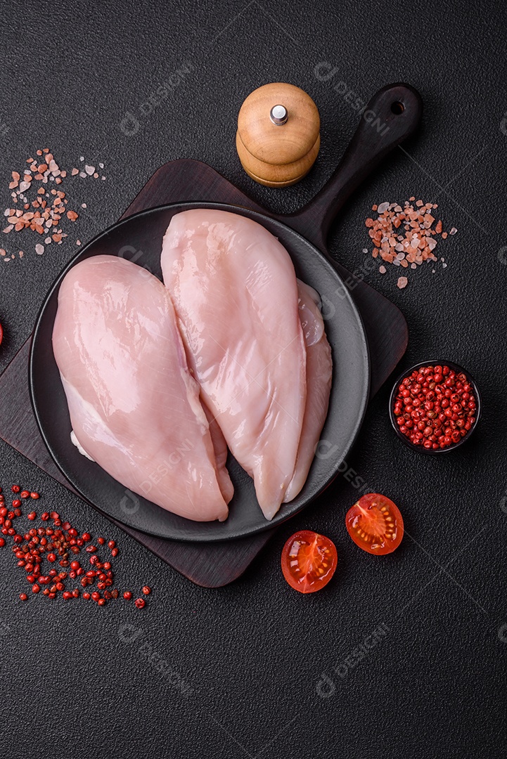 Filé de frango fresco sobre uma mesa de concreto escuro com especiarias e ervas. Preparação para cozinhar pratos de carne
