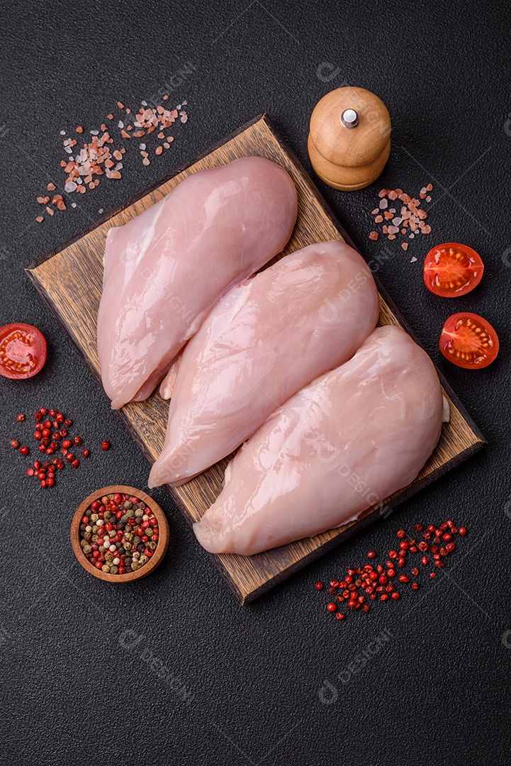 Filé de frango fresco sobre uma mesa de concreto escuro com especiarias e ervas. Preparação para cozinhar pratos de carne