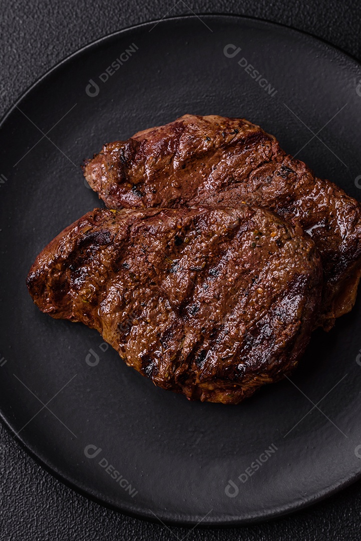 Bife fresco, suculento e delicioso em um fundo escuro. Prato de carne com especiarias e ervas