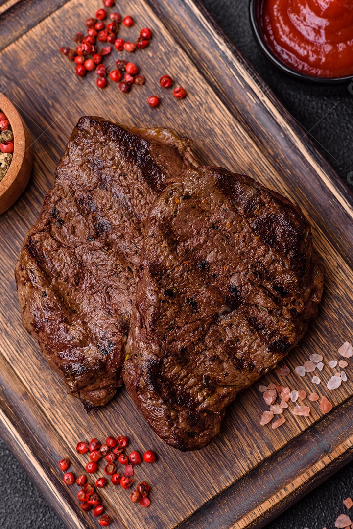 Bife fresco, suculento e delicioso em um fundo escuro. Prato de carne com especiarias e ervas