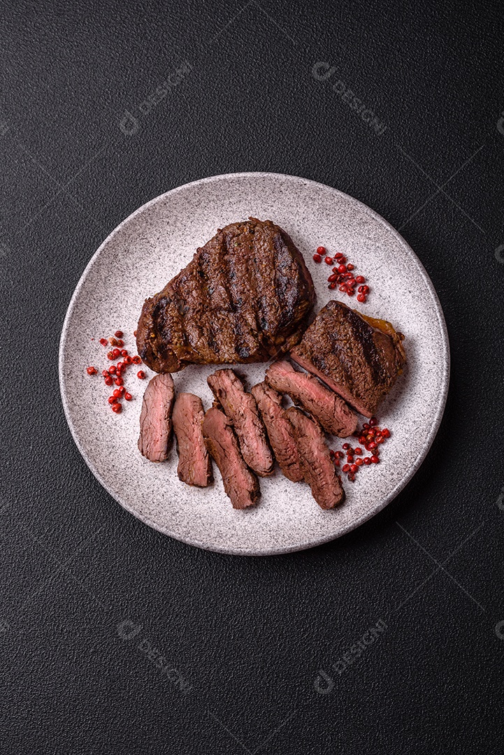 Bife fresco, suculento e delicioso em um fundo escuro. Prato de carne com especiarias e ervas
