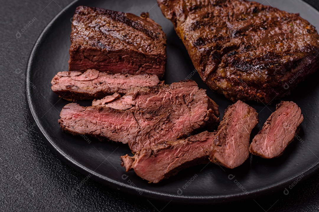 Bife fresco, suculento e delicioso em um fundo escuro. Prato de carne com especiarias e erva