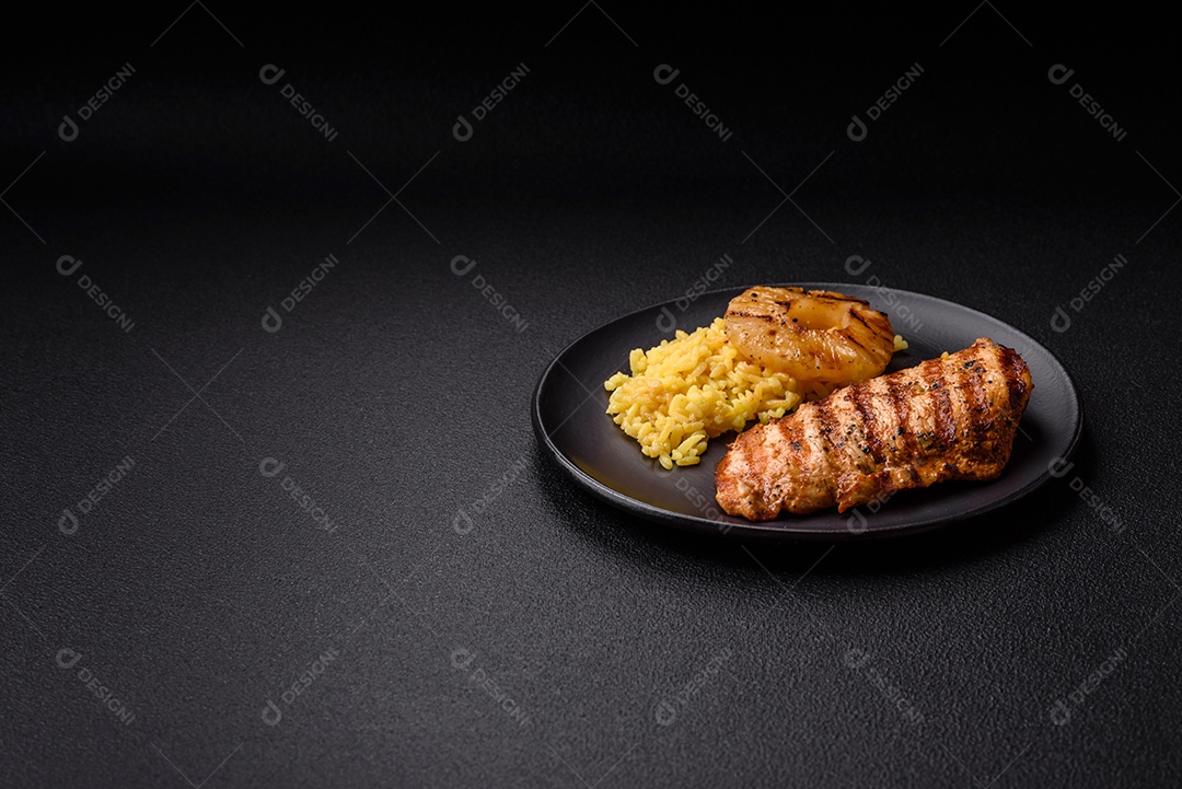 Delicioso filé de frango grelhado fresco com especiarias e ervas em um fundo escuro de concreto. Um prato cozido no fogo