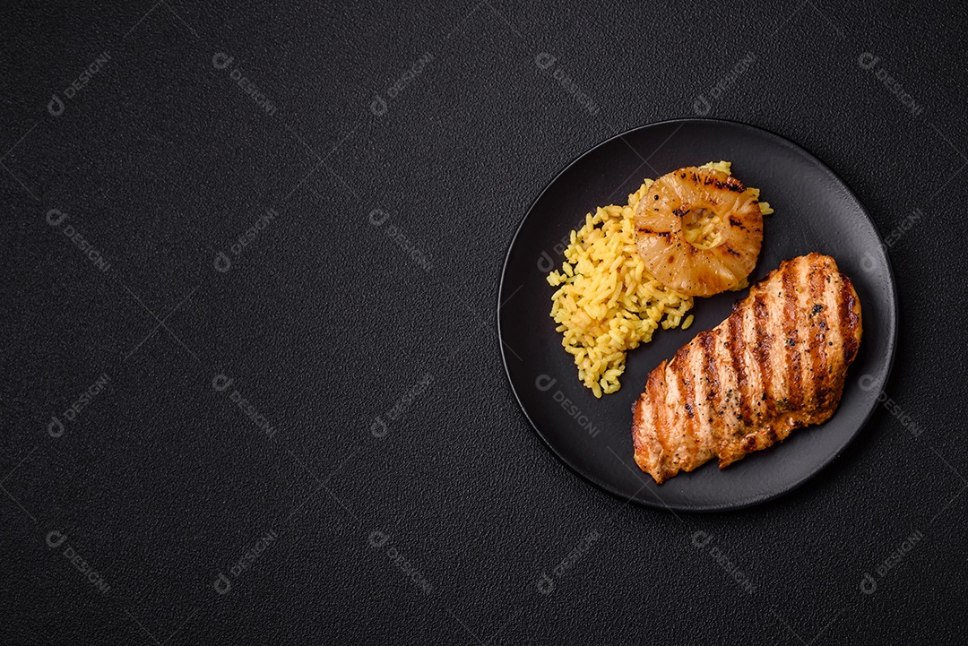 Delicioso filé de frango grelhado fresco com especiarias e ervas em um fundo escuro de concreto. Um prato cozido no fogo