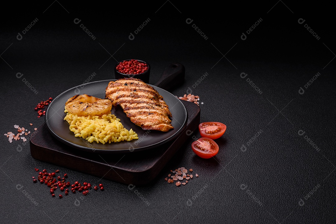 Delicioso filé de frango grelhado fresco com especiarias e ervas em um fundo escuro de concreto. Um prato cozido no fogo