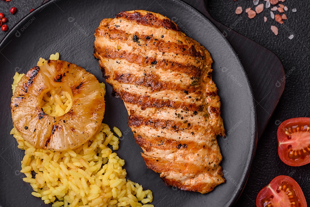 Delicioso filé de frango grelhado fresco com especiarias e ervas em um fundo escuro de concreto. Um prato cozido no fogo