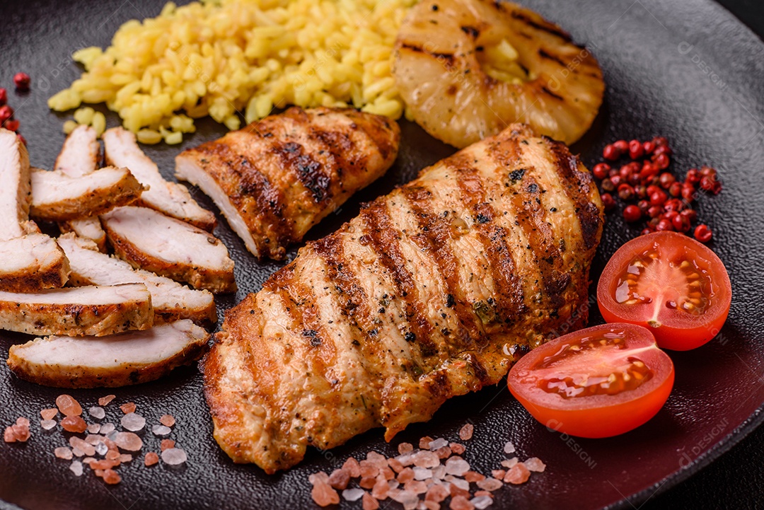 Delicioso filé de frango grelhado fresco com especiarias e ervas em um fundo escuro de concreto. Um prato cozido no fogo