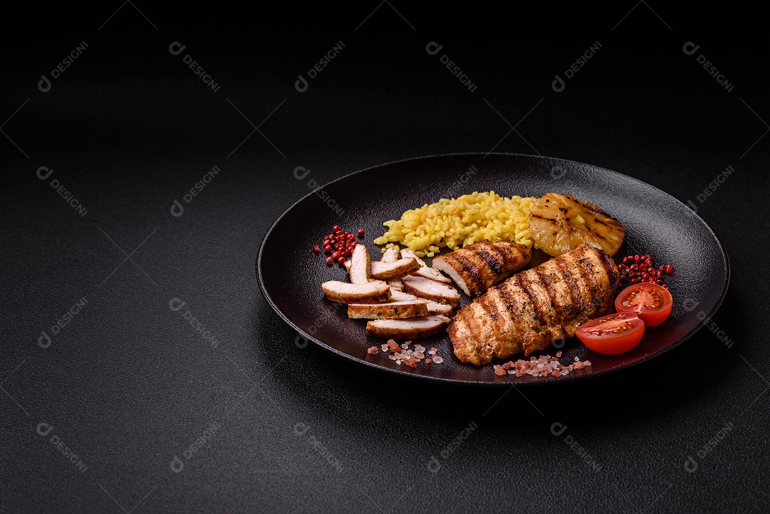 Delicioso filé de frango grelhado fresco com especiarias e ervas em um fundo escuro de concreto. Um prato cozido no fogo