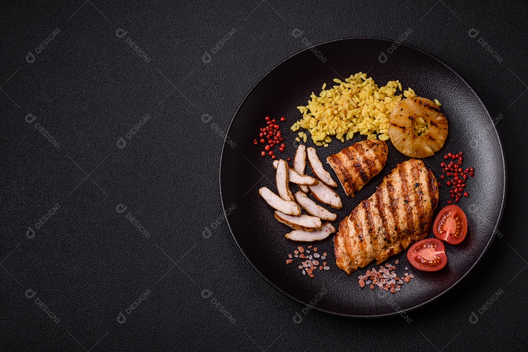 Delicioso filé de frango grelhado fresco com especiarias e ervas em um fundo escuro de concreto. Um prato cozido no fogo