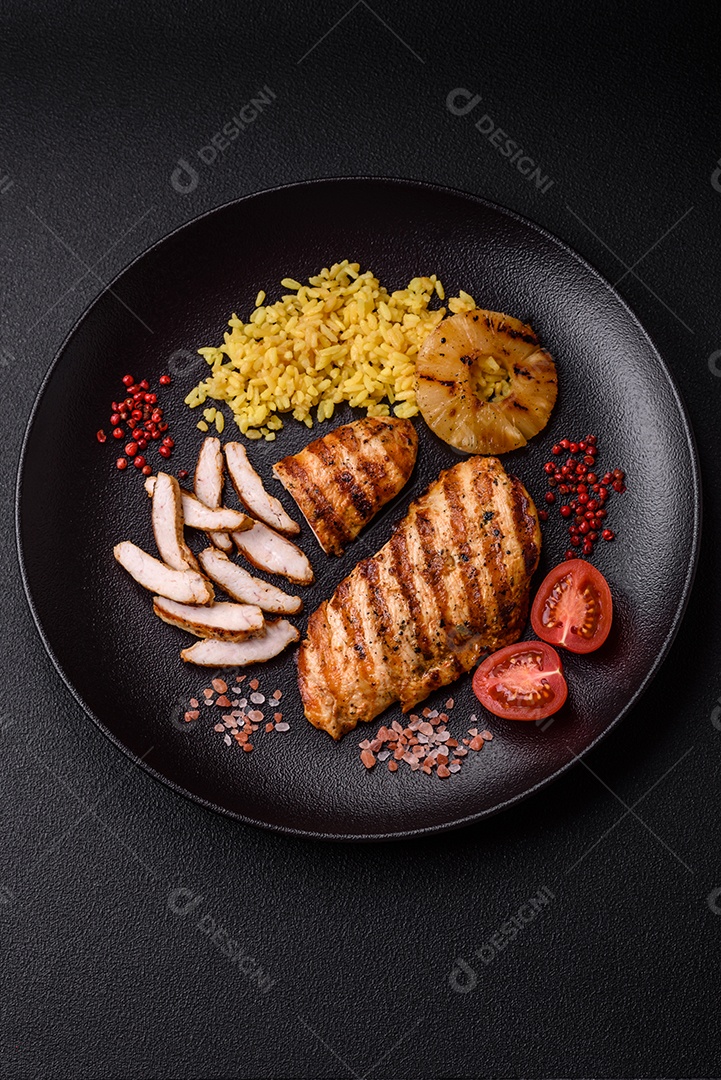 Delicioso filé de frango grelhado fresco com especiarias e ervas em um fundo escuro de concreto. Um prato cozido no fogo