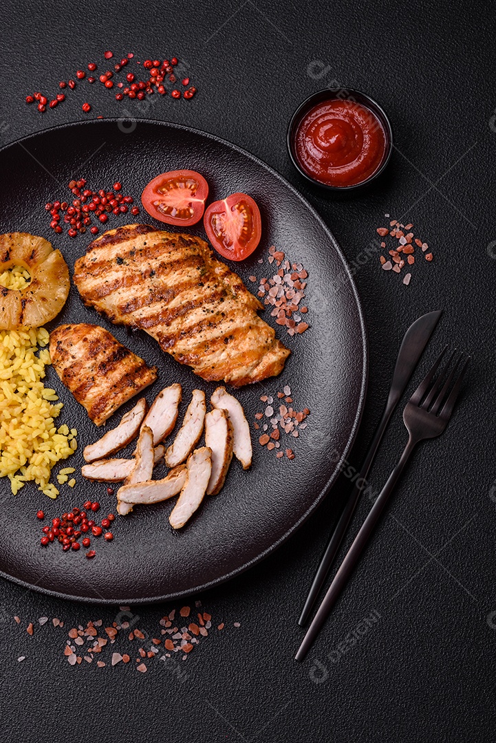 Delicioso filé de frango grelhado fresco com especiarias e ervas em um fundo escuro de concreto. Um prato cozido no fogo