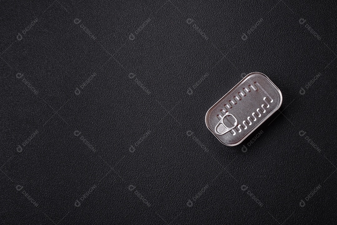 Lata retangular de peixe em óleo com sal e especiarias sobre fundo escuro de concreto