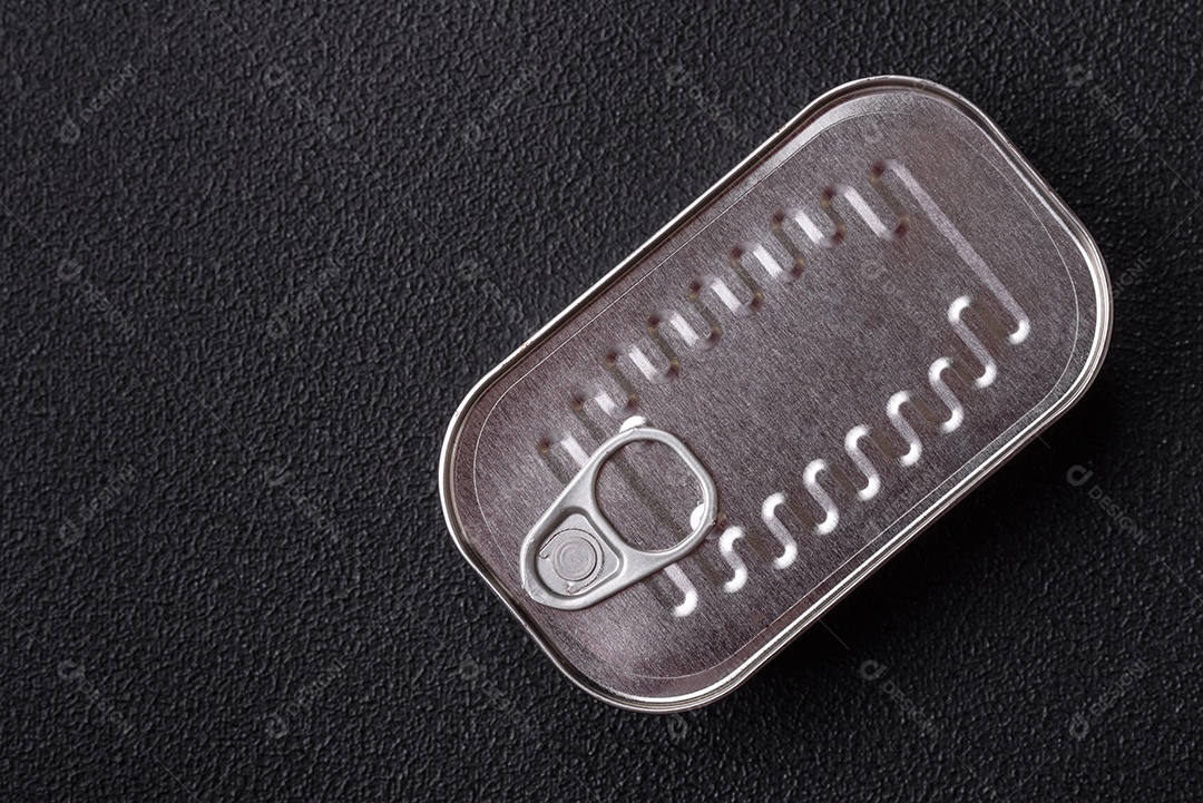 Lata retangular de peixe em óleo com sal e especiarias sobre fundo escuro de concreto