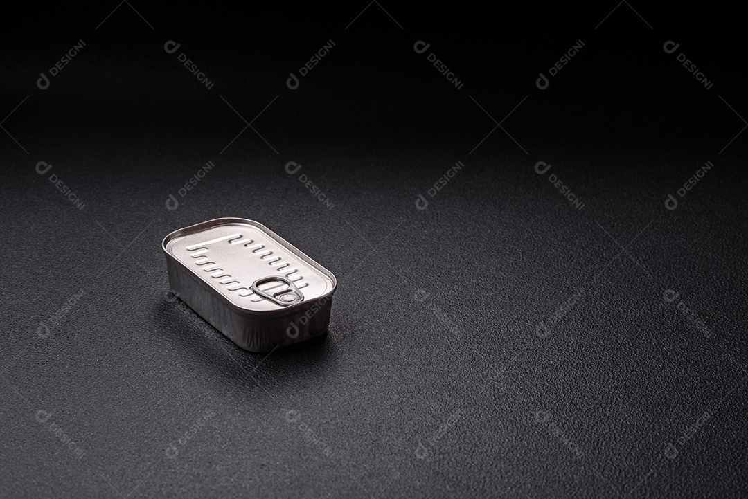 Lata retangular de peixe em óleo com sal e especiarias sobre fundo escuro de concreto