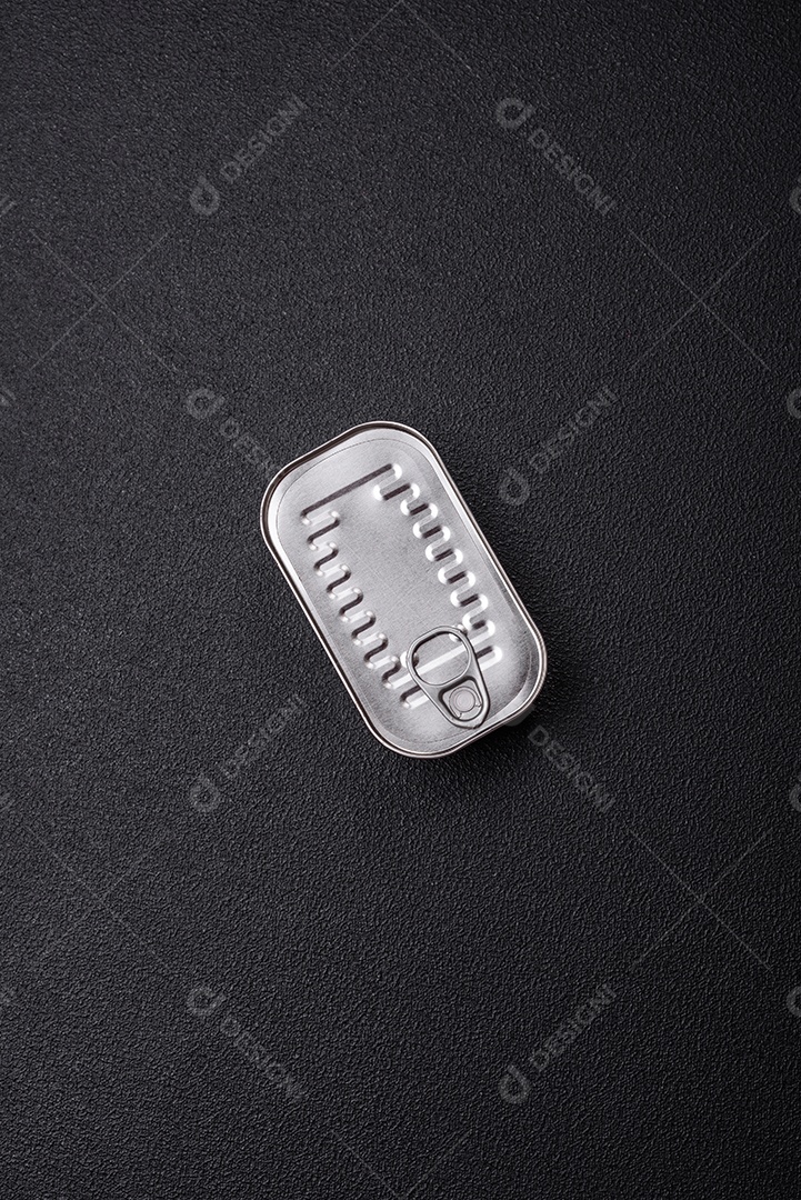 Lata retangular de peixe em óleo com sal e especiarias sobre fundo escuro de concreto