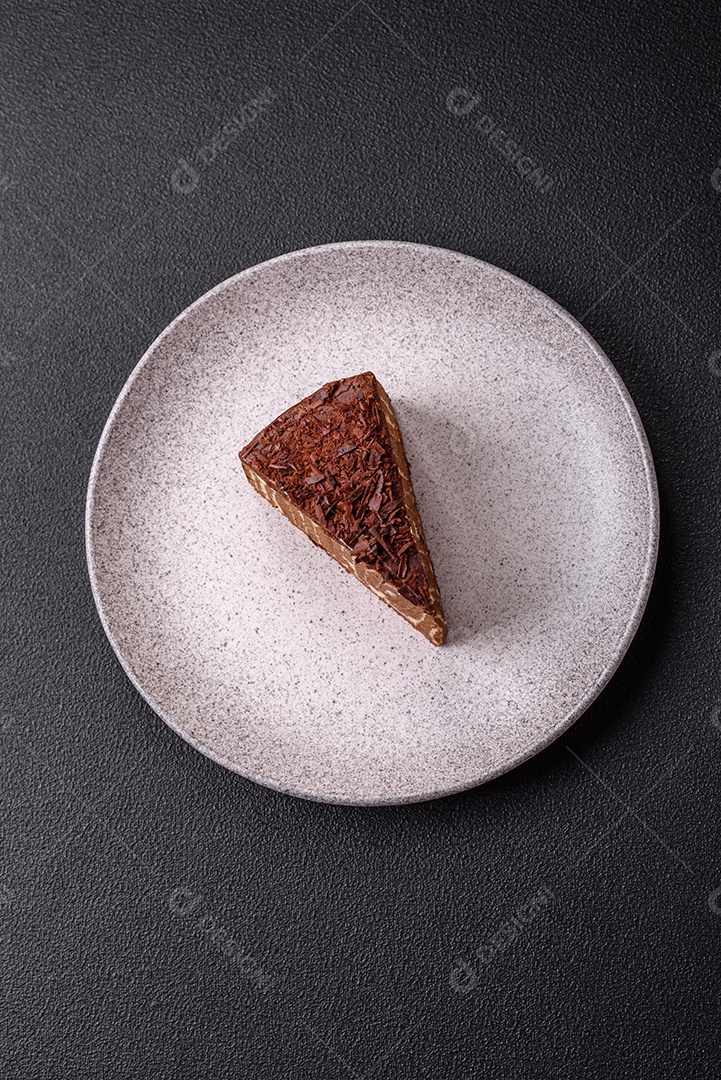 Delicioso bolo de queijo fresco ou snickers com creme e nozes em uma placa cerâmica sobre um fundo escuro de concreto