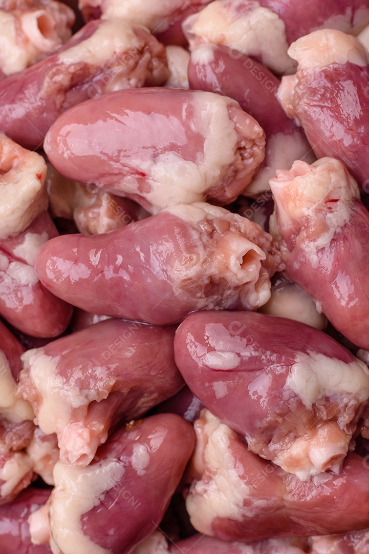 Corações de frango cru com sal, especiarias e ervas sobre um fundo escuro de concreto