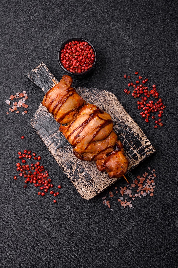 Delicioso kebab de frango ou carne de porco com sal, especiarias e ervas sobre um fundo escuro de concreto