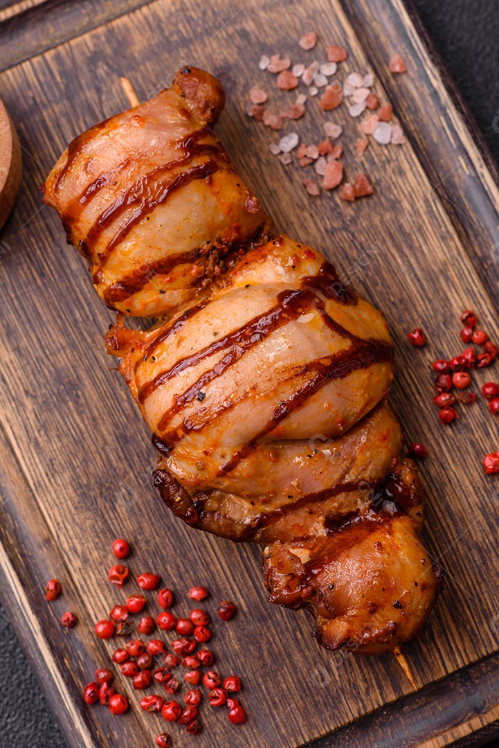 Delicioso kebab de frango ou carne de porco com sal, especiarias e ervas sobre um fundo escuro de concreto