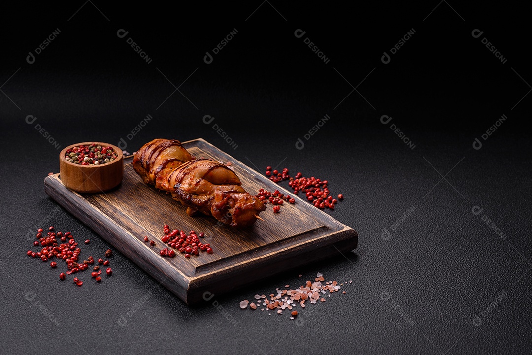 Delicioso kebab de frango ou carne de porco com sal, especiarias e ervas sobre um fundo escuro de concreto