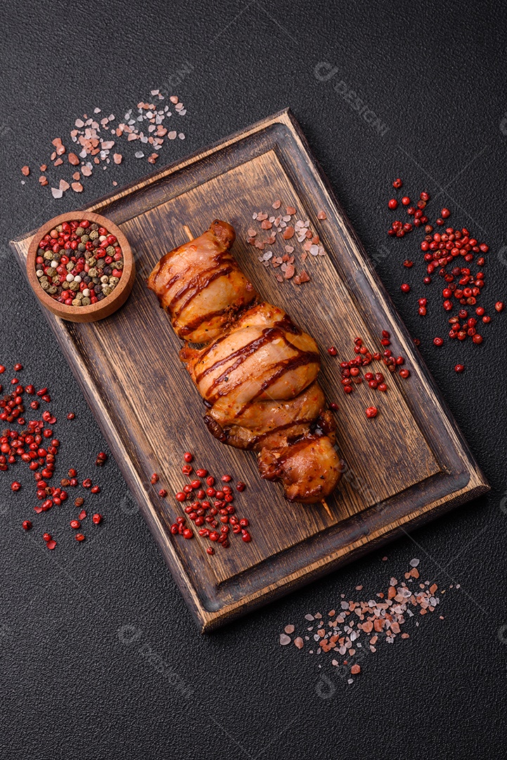 Delicioso kebab de frango ou carne de porco com sal, especiarias e ervas sobre um fundo escuro de concreto