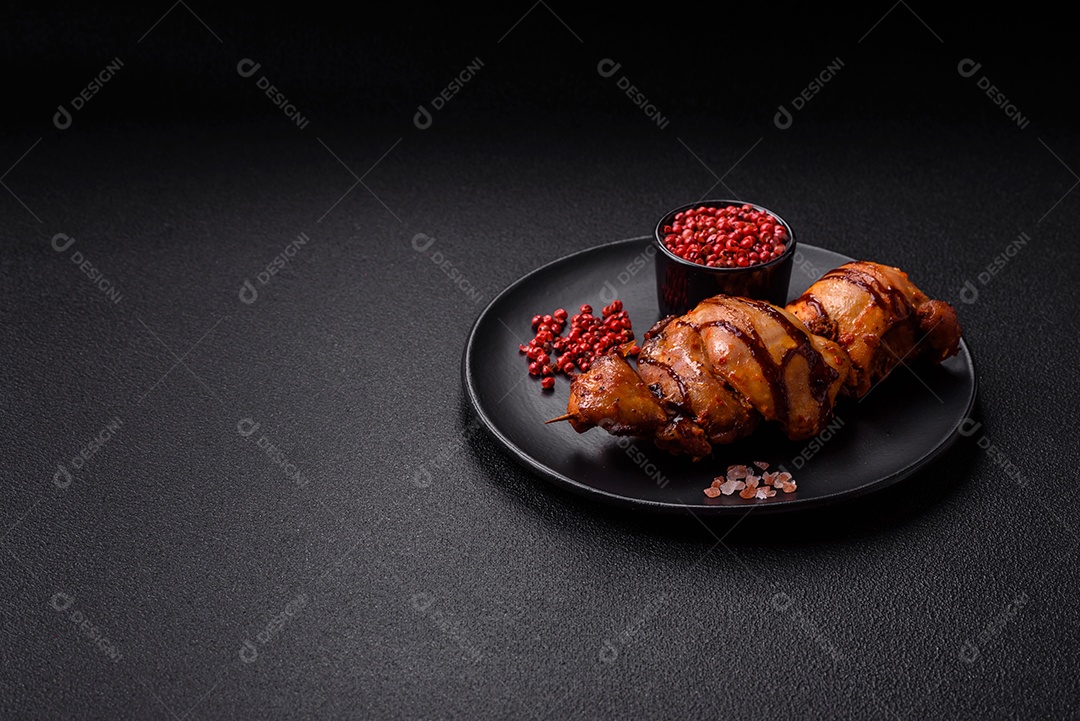 Delicioso kebab de frango ou carne de porco com sal, especiarias e ervas sobre um fundo escuro de concreto