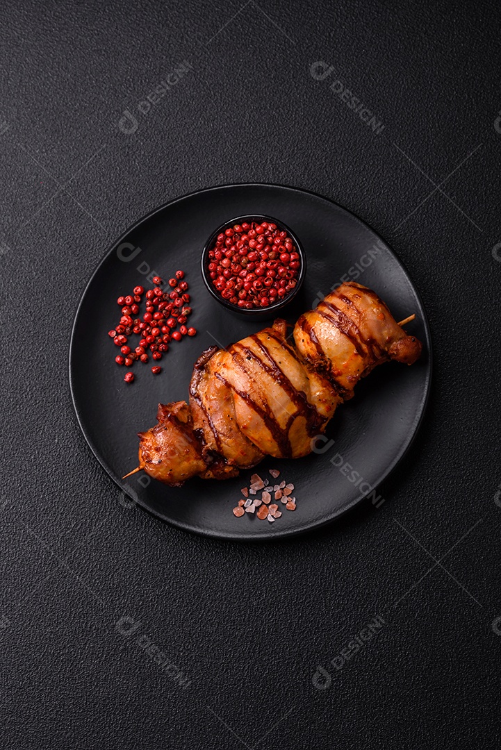 Delicioso kebab de frango ou carne de porco com sal, especiarias e ervas sobre um fundo escuro de concreto