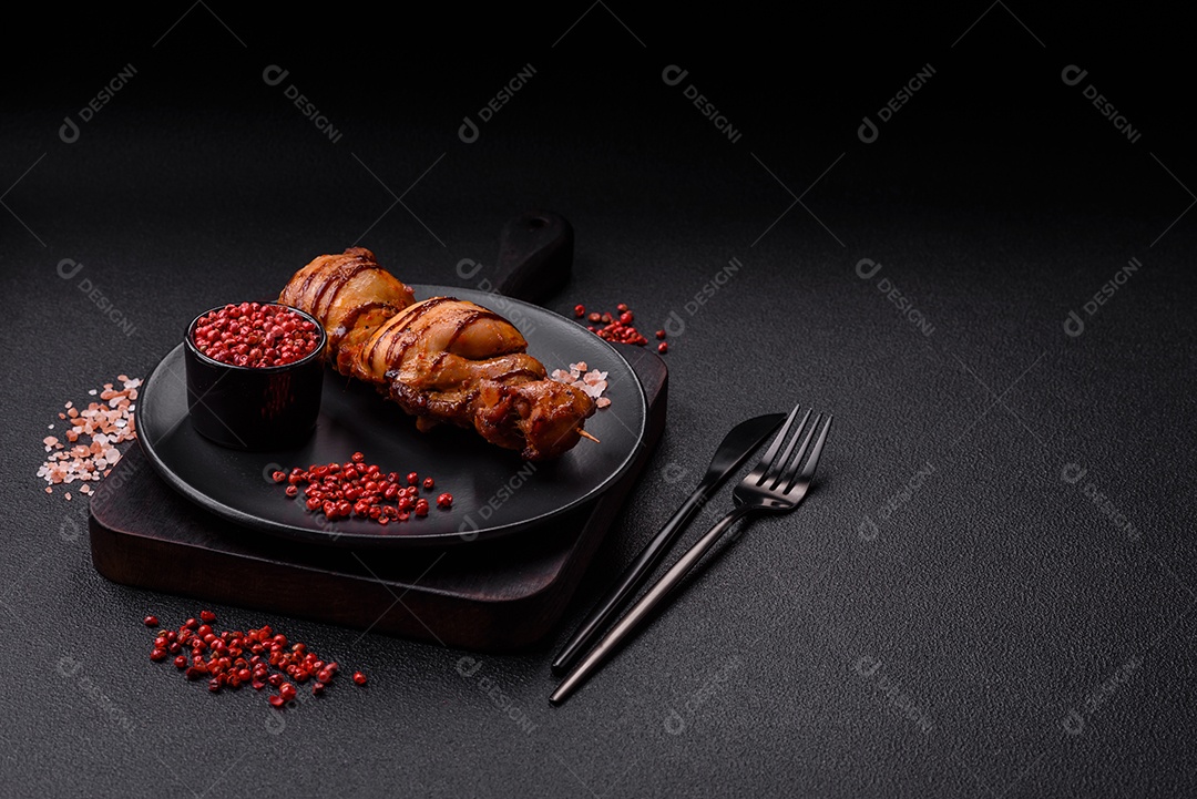 Delicioso kebab de frango ou carne de porco com sal, especiarias e ervas sobre um fundo escuro de concreto