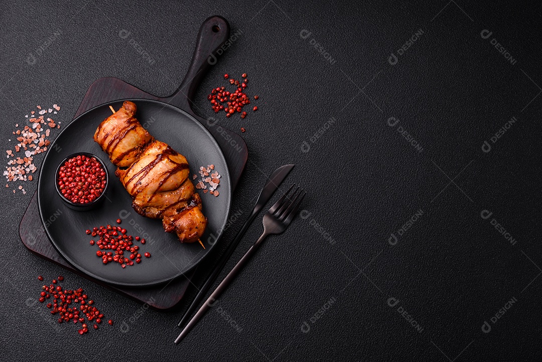 Delicioso kebab de frango ou carne de porco com sal, especiarias e ervas sobre um fundo escuro de concreto