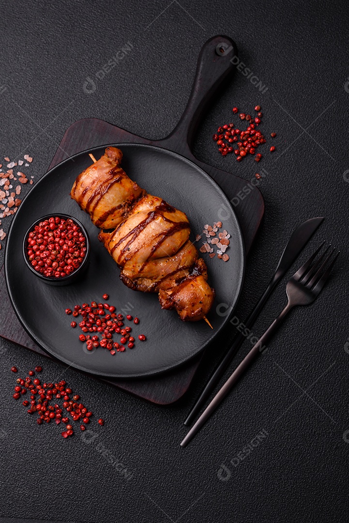 Delicioso kebab de frango ou carne de porco com sal, especiarias e ervas sobre um fundo escuro de concreto