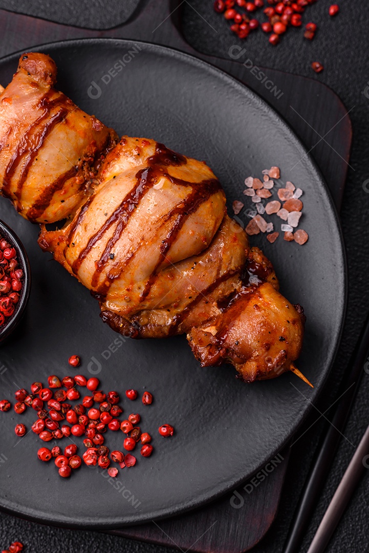 Delicioso kebab de frango ou carne de porco com sal, especiarias e ervas sobre um fundo escuro de concreto