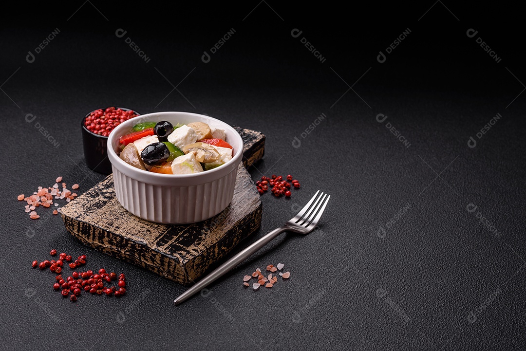 Deliciosa salada fresca e suculenta de pimentão, queijo, azeitonas, tomates, pepinos com sal e especiarias sobre um fundo escuro de concreto