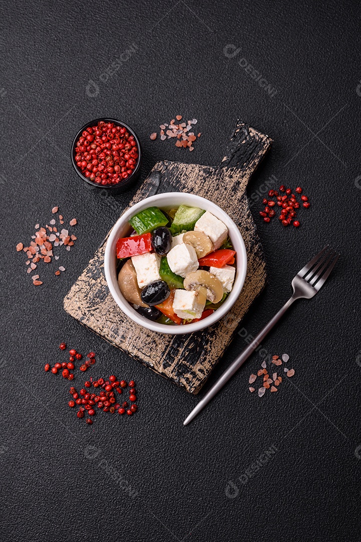 Deliciosa salada fresca e suculenta de pimentão, queijo, azeitonas, tomates, pepinos com sal e especiarias sobre um fundo escuro de concreto