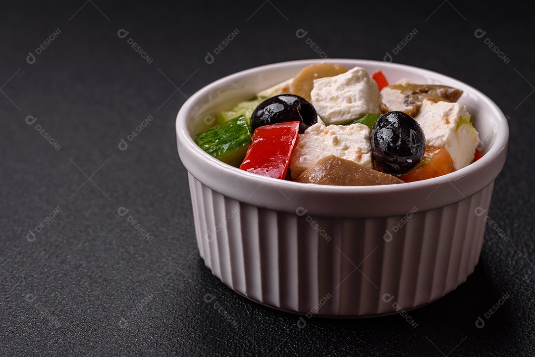 Deliciosa salada fresca e suculenta de pimentão, queijo, azeitonas, tomates, pepinos com sal e especiarias sobre um fundo escuro de concreto