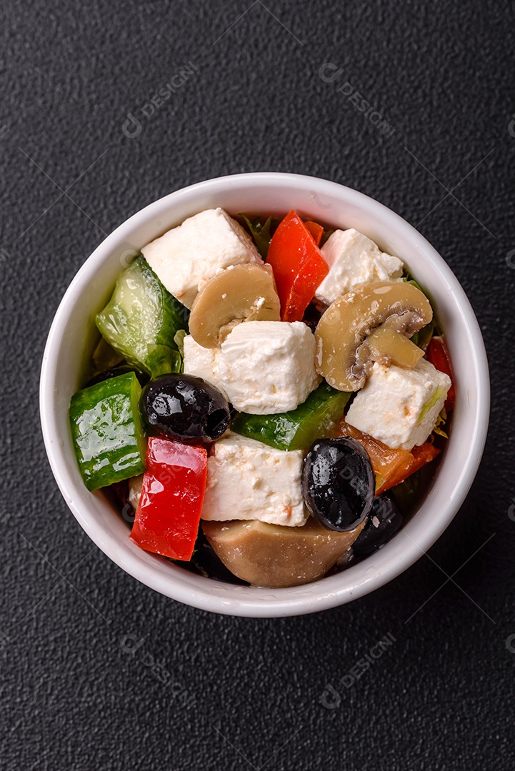 Deliciosa salada fresca e suculenta de pimentão, queijo, azeitonas, tomates, pepinos com sal e especiarias sobre um fundo escuro de concreto