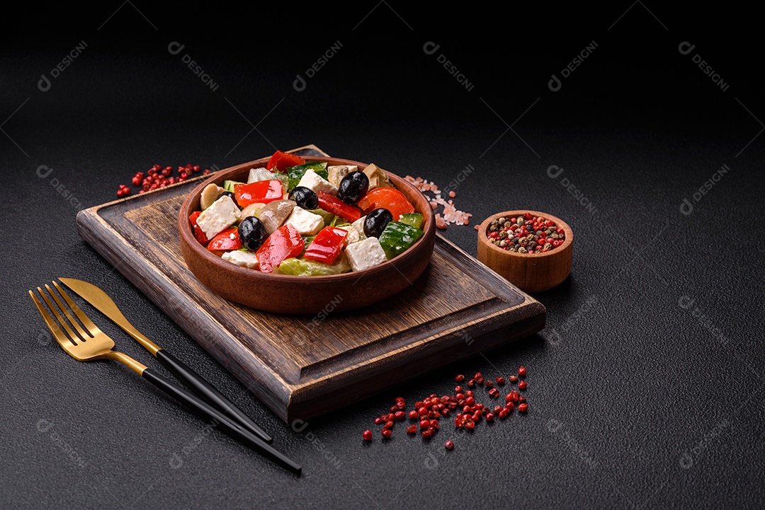 Deliciosa salada fresca e suculenta de pimentão, queijo, azeitonas, tomates, pepinos com sal e especiarias sobre um fundo escuro de concreto
