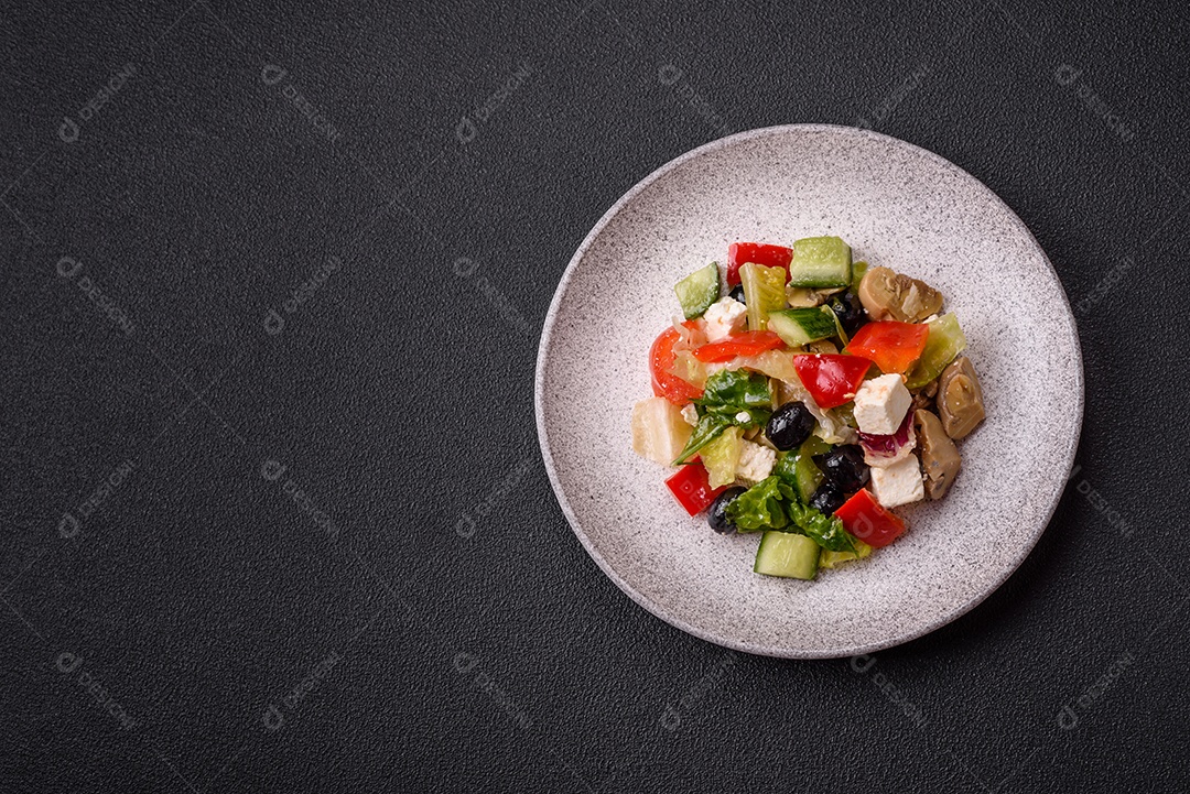 Deliciosa salada fresca e suculenta de pimentão, queijo, azeitonas, tomates, pepinos com sal e especiarias sobre um fundo escuro de concreto
