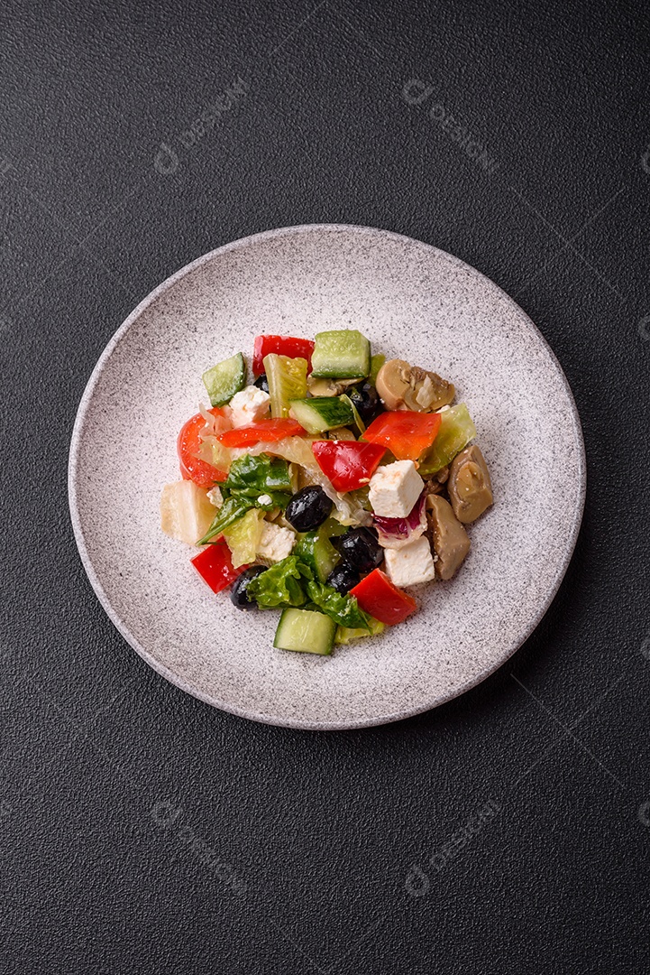 Deliciosa salada fresca e suculenta de pimentão, queijo, azeitonas, tomates, pepinos com sal e especiarias sobre um fundo escuro de concreto