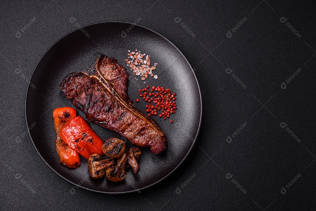 Delicioso bife suculento com sal, especiarias e ervas sobre um fundo escuro de concreto
