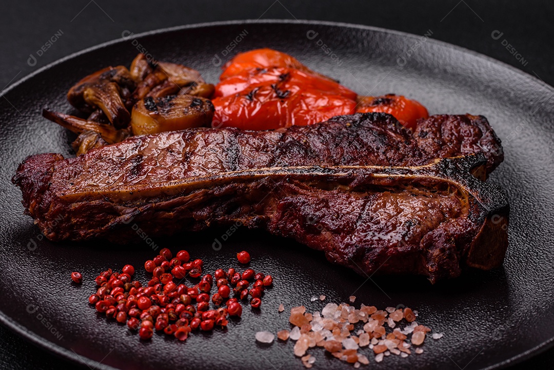 Delicioso bife suculento com sal, especiarias e ervas sobre um fundo escuro de concreto
