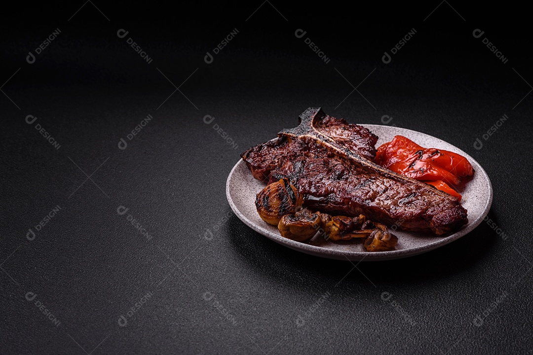 Delicioso bife suculento com sal, especiarias e ervas sobre um fundo escuro de concreto