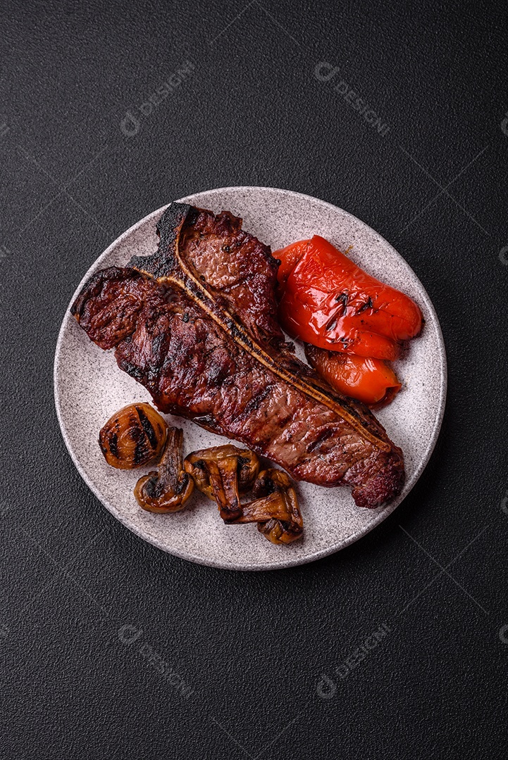 Delicioso bife suculento com sal, especiarias e ervas sobre um fundo escuro de concreto