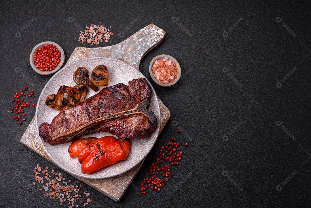 Delicioso bife suculento com sal, especiarias e ervas sobre um fundo escuro de concreto