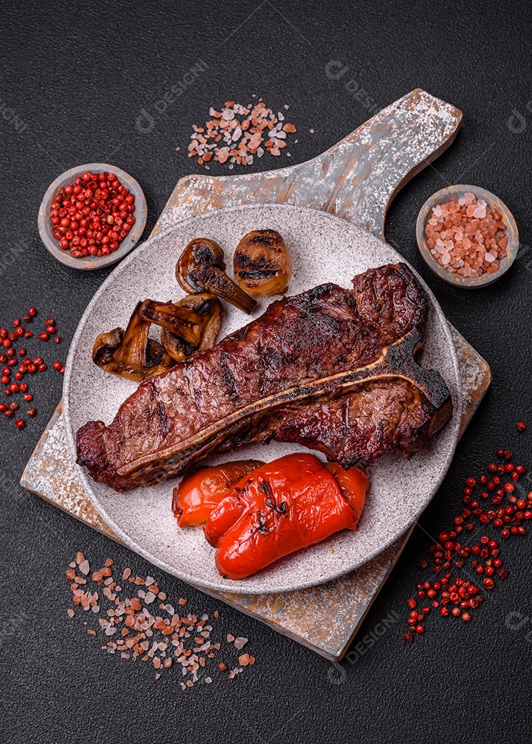 Delicioso bife suculento com sal, especiarias e ervas sobre um fundo escuro de concreto