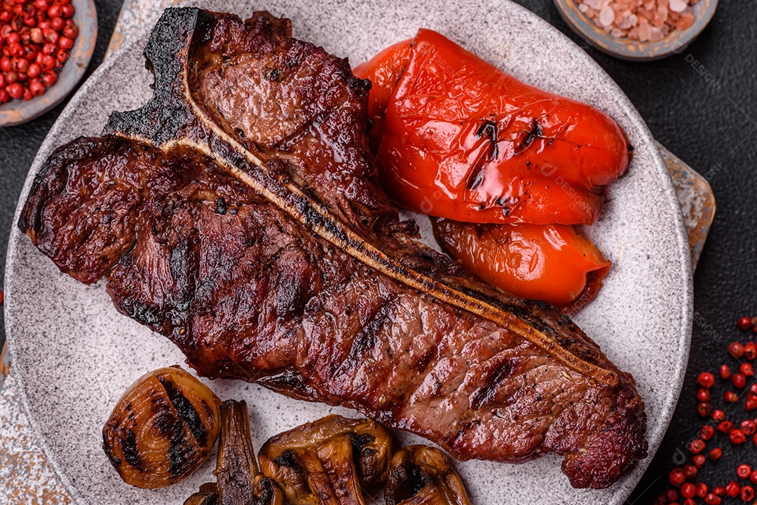 Delicioso bife suculento com sal, especiarias e ervas sobre um fundo escuro de concreto