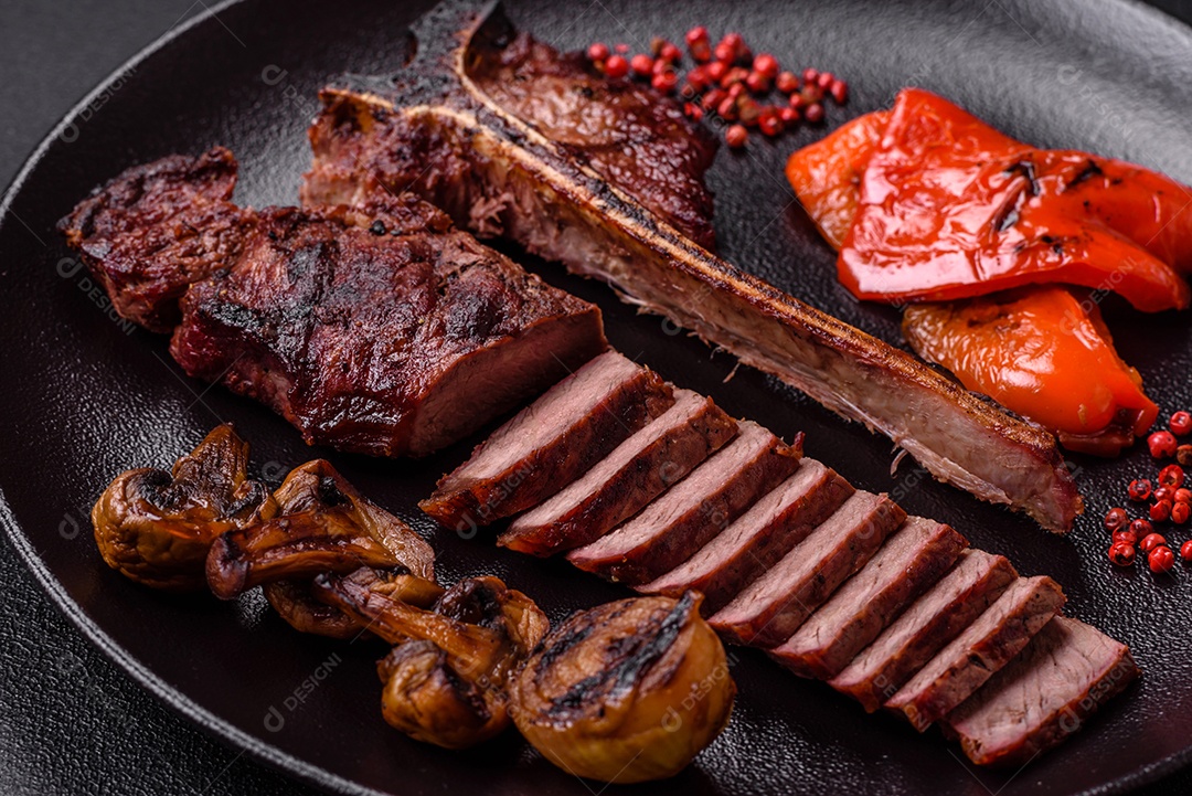 Delicioso bife suculento com sal, especiarias e ervas sobre um fundo escuro de concreto